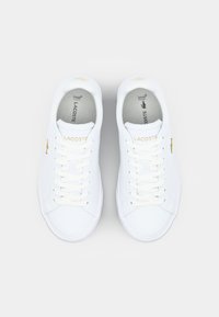 Hvite lær sneakers med flate hvite snøringer, en teksturert tåhette og subtile gulllogo-aksenter. Polstrede såler for komfort.