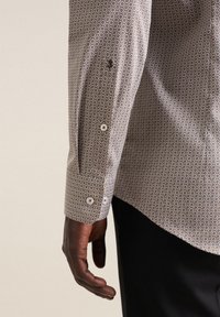 Koszula z guzikiem z geometrycznym wzorem w odcieniach brązu i szarości, w slim fit, z zapięciami na guziki przy mankietach oraz subtelnym haftowanym logo.
