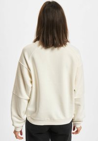 Cremfarbener, übergroßer Hoodie mit strukturiertem Rücken und Raglanärmeln, mit gerippten Bündchen und Saum. Weicher Stoff.
