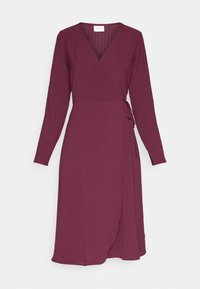 Långärmad, ribbad ombrett klänning i djup plommon med sidoknyte, V-ringning och midilängd.