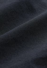 Tissu sombre avec une surface lisse et légèrement texturée, présentant une couleur bleu marine profond et un fin motif de tissage diagonal.