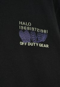 Schwarzer Stoff mit lila Reifenspuren, darüber der Text "HALO 196819721981" und darunter die Aufschrift "OFF DUTY GEAR" neben der Grafik.