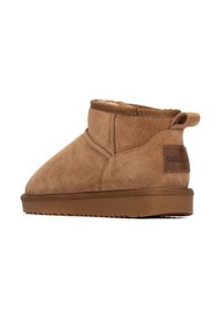 Botas de tobillo de ante color topo con puntera redondeada, forro de borreguillo y suela de goma. Cuenta con una tira en la parte trasera y un parche de marca en el lado.