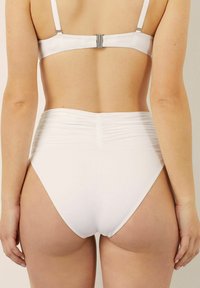Witte bikini set met een gemetalliseerde achterkant en een hooggesneden onderkant. De bandjes zijn verstelbaar met een metalen sluiting.