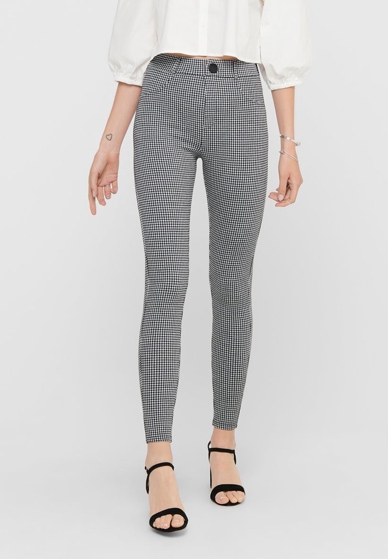Zwart-witte legging met een houndstooth patroon, voorzien van een aansluitende silhoeet, hoge taille en een zachte textuur.