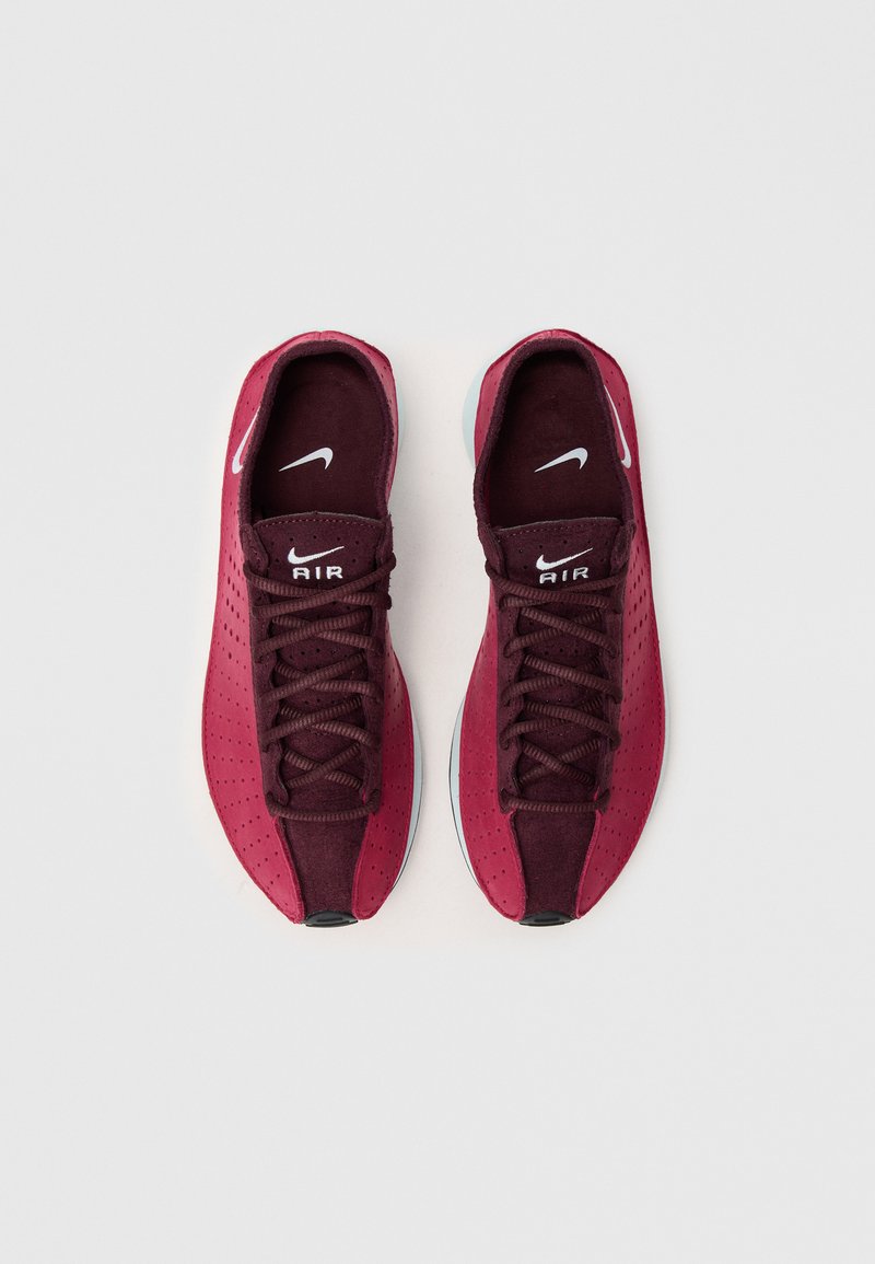 Zapatillas deportivas color burdeos con parte superior sintética perforada, cordones planos y suela de goma. Presenta el logo blanco de Nike y el texto "AIR" en la lengüeta.