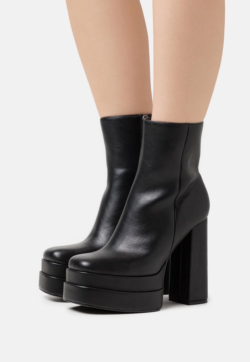 Black leather ankle boots with a smooth texture, high block heels, and a platform sole. Features a side zipper for closure.