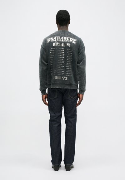 Hall gray sweatshirtil on tekst ja graafika printidega seljal, kombineeritud tumedate teksadega. Sweatshirtil on ümar kaelus ja soonikääred.