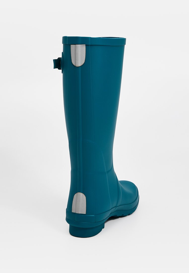 Bota de goma verde azulado con una superficie lisa, caña alta, acentos grises en la parte superior y el talón, y una suela moldeada para una mejor tracción.