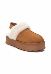 Scarpa slip-on color corda con una morbida fascia di pelliccia bianca nella parte anteriore, una robusta suola piattaforma marrone e una finitura in suede liscia.