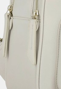 Borsa a mano grigia chiara con esterno texturizzato, accessori in tonalità oro, doppi zip e cuciture a contrasto lungo i bordi.