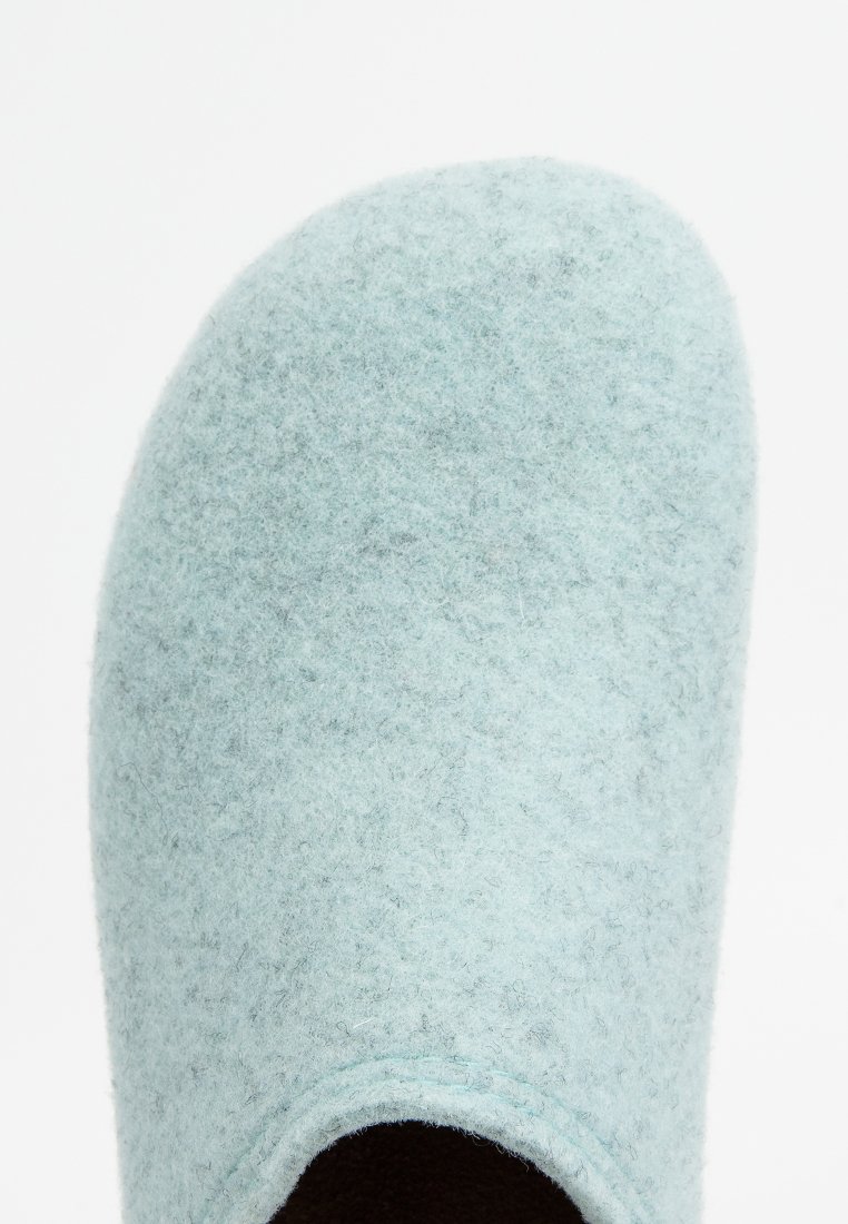 Hellblauer Filzschuh mit abgerundetem Zehenbereich und offener Ferse, der eine weiche Textur und ein dunkles Innenfutter zeigt.