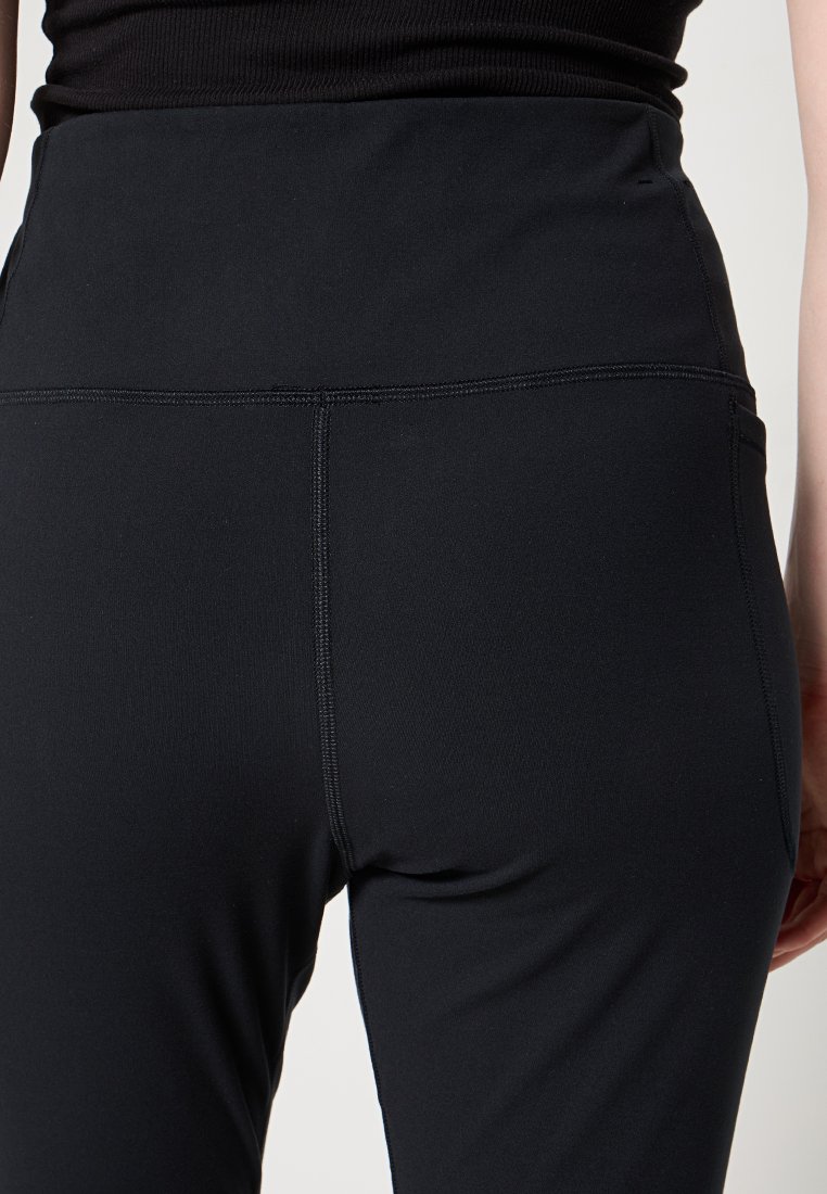 Leggings neri con un alto elastico in vita, realizzati in un tessuto liscio e elasticizzato. Presentano cuciture piatte e una silhouette aderente.