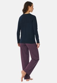 Maglietta a maniche lunghe blu navy abbinata a pantaloni da pigiama viola con stampa a motivo geometrico. Tessuto morbido con vestibilità comoda.