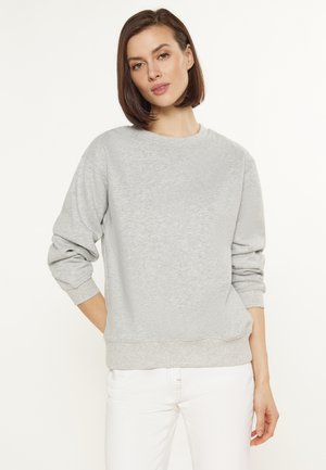 Lys grå sweatshirt med rund hals, ribbede manchetter og kant, blød tekstur og dropped shoulders, parret med hvide bukser.
