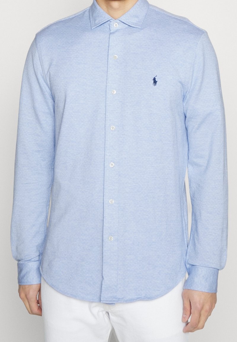 Camicia button-up azzurro chiaro realizzata in tessuto testurizzato, con maniche lunghe, colletto aperto e un piccolo logo ricamato sul petto.