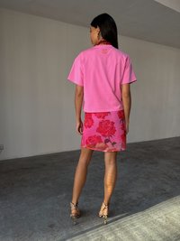 Maglietta di cotone rosa con un design leggermente cropped e gonna rosa a fantasia floreale con rose. Abbinata a sandali con tacco leopardati.
