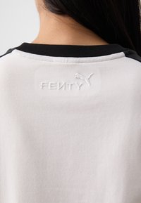 A close-up of the back of a shirt showcasing black and white fabric, featuring the embossed "FENTY" logo and Puma emblem.