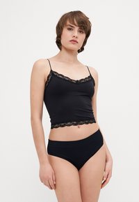 Černá halenka s krajkovým lemem, tenkými ramínky a odpovídajícími kalhotkami s vysokým pasem. Hladký, pružný materiál, přiléhavý design.