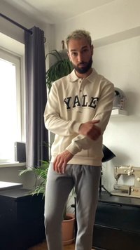 Krém színű polo póló, amelyen a "YALE" felirat sötétkék színben található, hosszú ujjak és gombos nyakrésszel; világosszürke, taperd fazonú nadrággal párosítva. Belső tér.