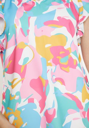 Bluză multicoloră strălucitoare cu modele florale abstracte în roz, galben, albastru și alb, purtată pe partea superioară a corpului unei persoane.