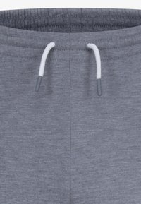 Grå joggebukser med snor i midjen og hvit snor, glatt tekstur og sidesømmer. Minimalistisk design med en avslappet passform.