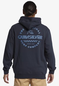 Námornícky modrá mikina s kapucňou so veľkým svetlomodrým grafickým motívom na chrbte. Obsahuje zaoblený dizajn loga s textom "Quiksilver" a kockovaným vzorom.