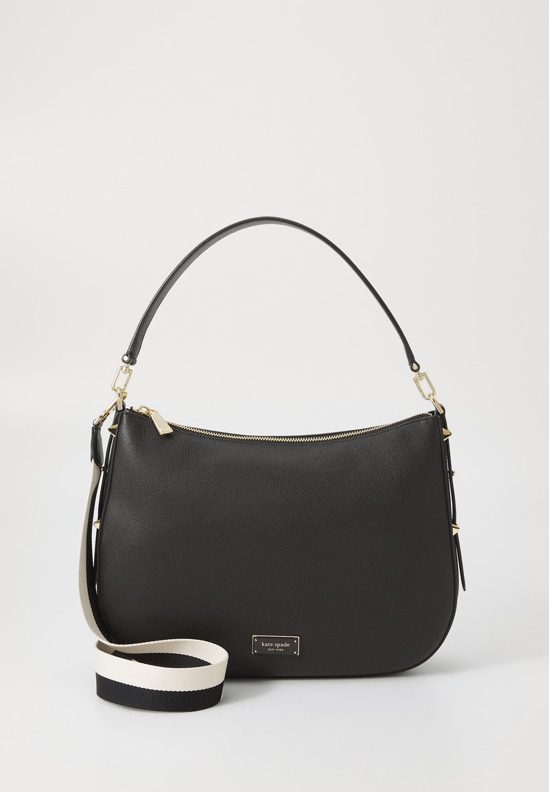 Black leather handbag with curved shape, gold zipper, and logo plate. Includes a detachable strap featuring black and white color blocking.