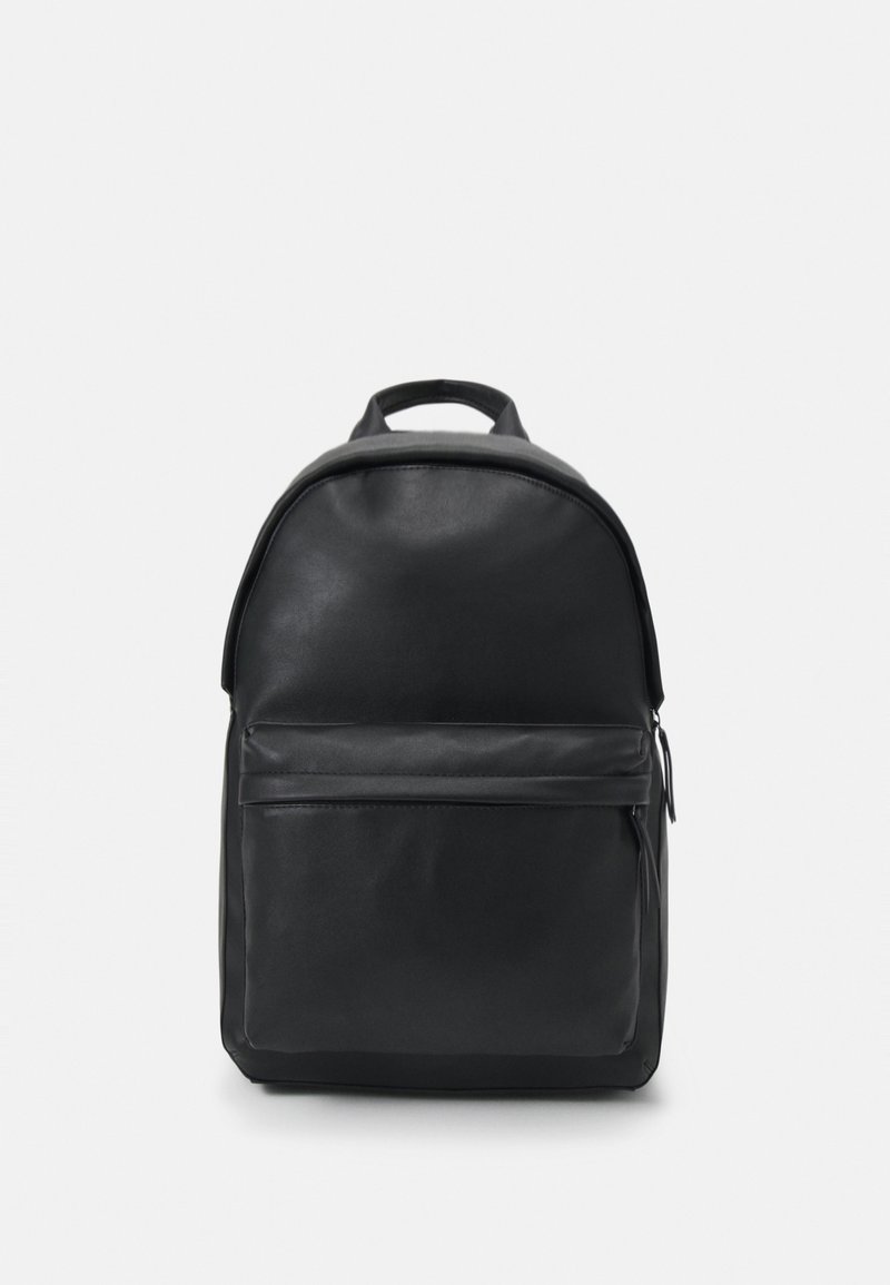 Sac à dos en cuir noir avec un haut arrondi, une poche zippée à l'avant et une poignée de transport. La surface est lisse avec des accents minimaux.