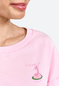 Lichtroze katoenen t-shirt met een ronde hals, voorzien van een geborduurde afbeelding van spaghetti en een vork in roze en groene accenten.