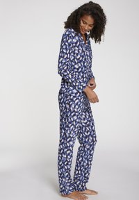 Langarm pyjama set in blauw met een contrasterend abstract patroon in wit en licht beige. Gemaakt van zachte stof, met een knoopsluiting aan de voorkant.