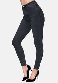 Jeans ajustados de cintura alta en denim gris oscuro. Con bolsillos laterales, cierre delantero con botón y un ajuste ceñido. Acentuados con tacones altos negros.