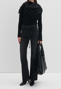 Musta ribbeltoppi pitkillä hihoilla, korkeavyötäröiset mustat farkut ja ylisuuri musta nahkabag. Mustat nilkkurit viimeistelevät asun.