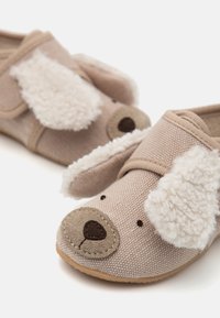 Brune tøfler med teksturert stoff, med faux pelsører og nesedesign. Borrelås-lukking for enkel påkledning. Myk indre fôr.