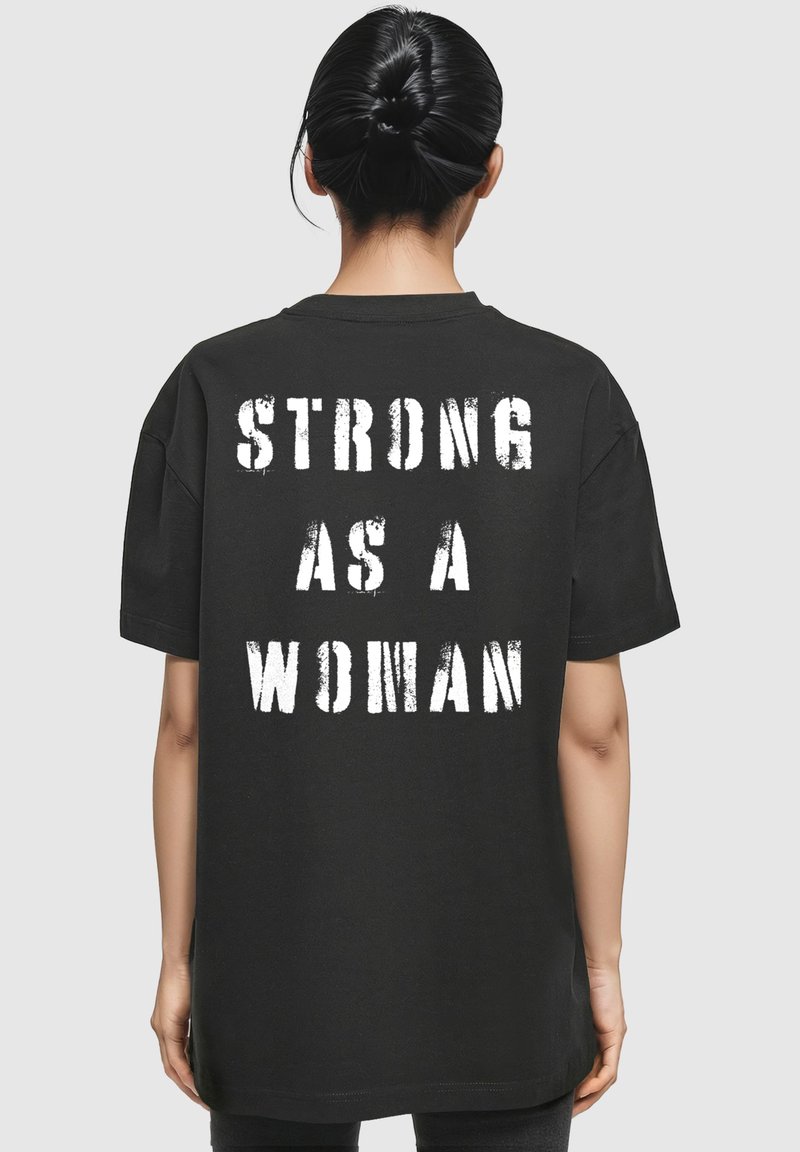 Sort t-shirt med korte ærmer, prydet med fed hvid tekst på ryggen, der står "STÆRK SOM EN KVINDE." Standard pasform, lavet af bomuldsmateriale.