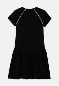 Fekete ruha rövid ujjal, kerek nyakkivágással, testhezálló felsőrésszel és bővülő fodros szegéllyel. Fehér díszítésekkel szegélyezve.