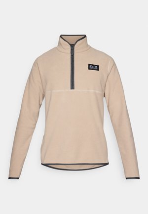 Beige fleece-pullover med halvklar och kontrasterande mörk kant, samt en liten logopatch på vänster bröst. Långa ärmar och rundad nederkant.