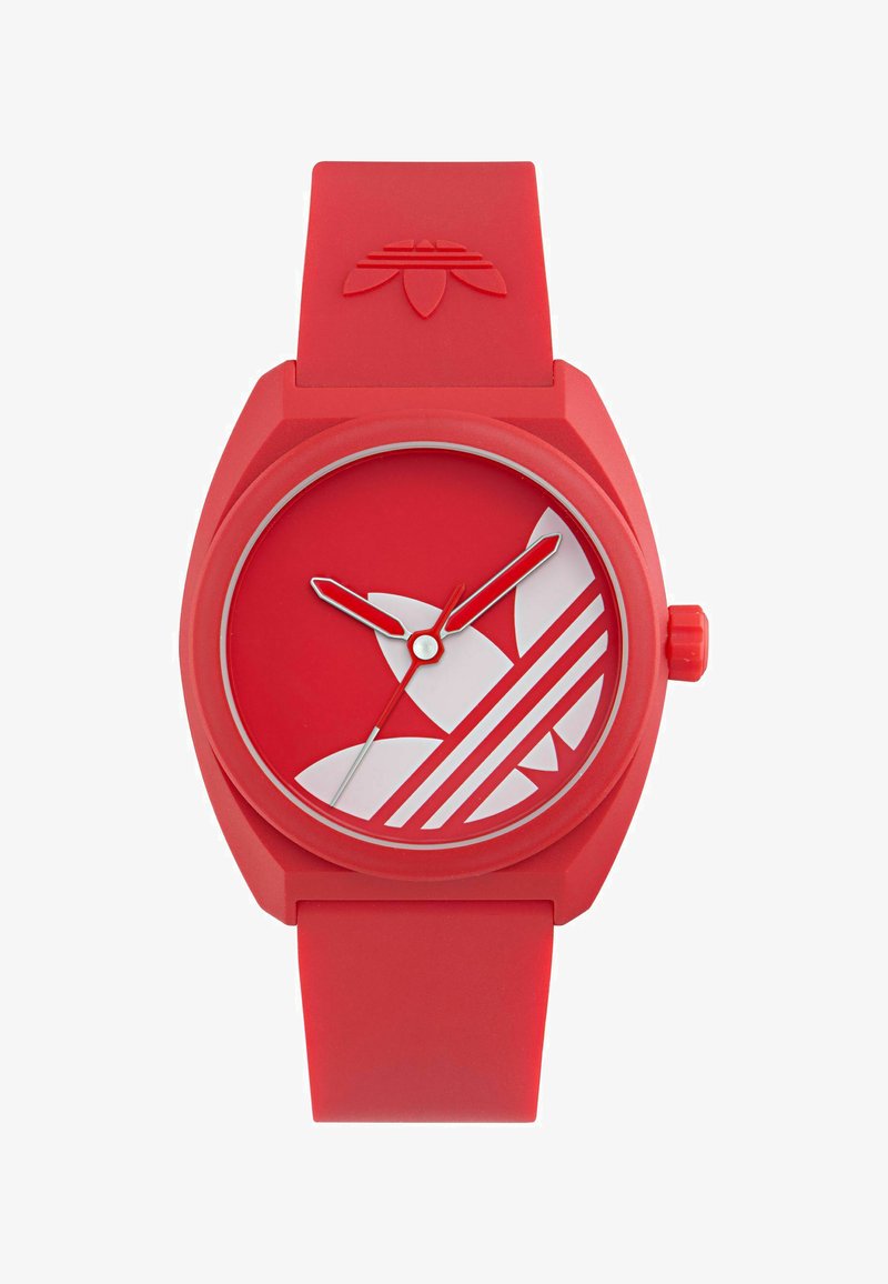 Rødt silikoneur med rund urskive, hvidt Adidas-logo, hvide timeindeks og røde time- og minutvisere. Drejekrone på siden.