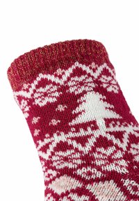 Rote gestrickte Socke mit weißen und hellrosa geometrischen Mustern, einschließlich Bäume. Verfügt über einen gerippten oberen Rand mit einem goldenen Fadenakzent.