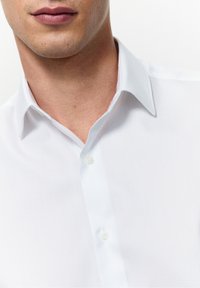 Witte overhem shirt met een klassieke kraag en een gladde, gestructureerde stof, met een enkele knoopsluiting bij het halsgebied.