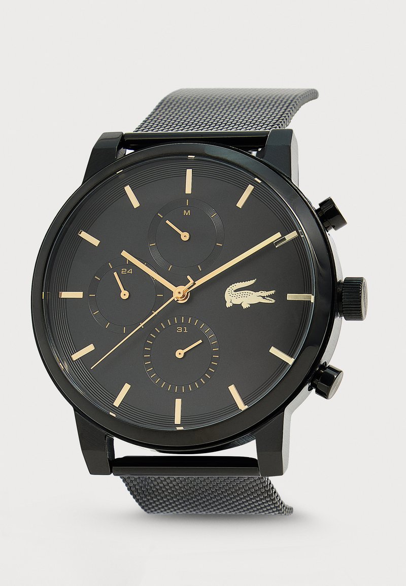 Montre-bracelet noire avec des repères d'heure dorés, trois sous-cadrans, un bracelet en maille métallique et un logo crocodile sur le cadran.