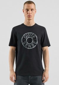 Czarna bawełniana koszulka z okrągłym nadrukiem w szarym kolorze z napisem „QUIET SENSE.” Okrągły dekolt, krótkie rękawy i luźny krój.