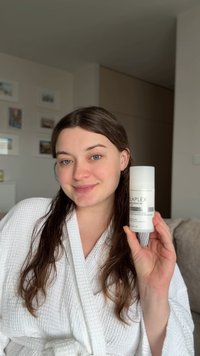 Olaplex No. 5 Leave-In, flacon blanc, forme cylindrique, design minimaliste, avec du texte noir. Modèle portant un peignoir texturé blanc, tenant le produit.