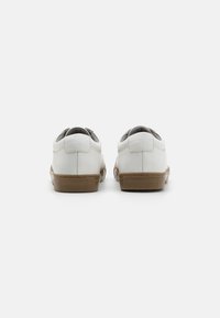 White leather shoes with a round toe and a sturdy brown rubber sole. Features a smooth texture and minimalistic design.