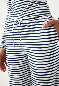 Randigt lounge-set i marinblått och vitt, med dragsko i midjan, lättviktstyg och sidfickor. Enkel och funktionell design.