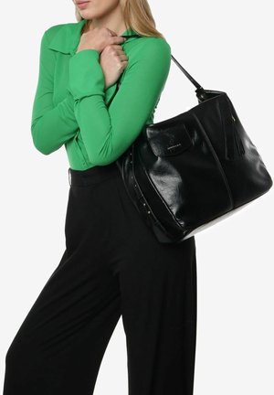 Borsa in pelle nera con una finitura lucida, dotata di manico superiore e chiusura con cerniera, appoggiata su una blusa verde.
