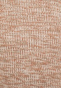 Stickat tyg i nyanser av beige, orange och brunt, som har ett texturerat, alternerande mönster med vertikala linjer och en mjuk, elastisk känsla.