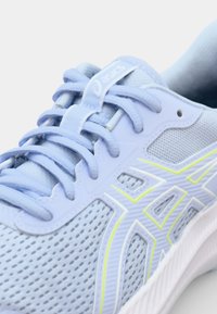 ZS Zapatilla deportiva azul claro con parte superior de malla, acentos amarillos en contraste, cordones planos y una suela gruesa blanca con un agarre de goma texturizada.