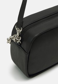 Black leather bag with a rectangular shape, featuring a zipper closure and a metallic chain accent on the strap. Textured surface.