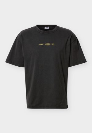 Black short-sleeve crew neck t-shirt with small yellow graphic including "ARKK" text and abstract symbols centered on the chest.
